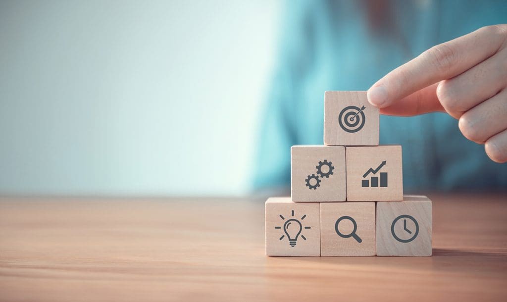 Blocks stacked together in a pyramid with different business strategy icons on them.