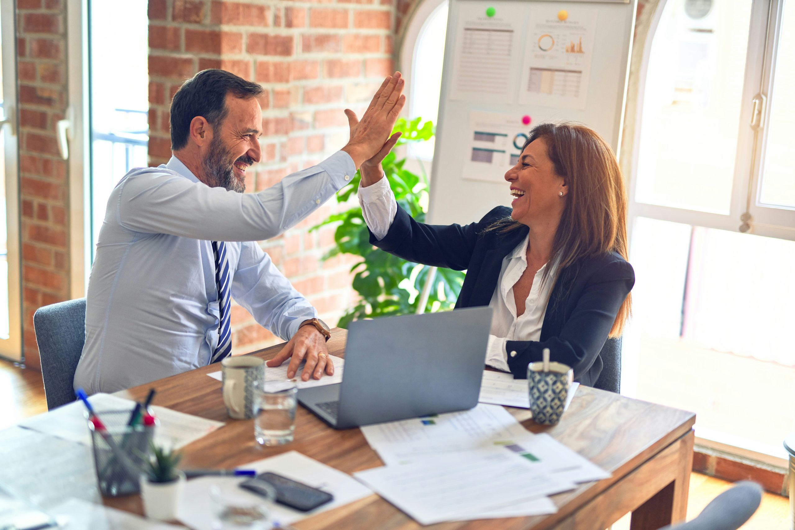 Two people high fiving after hardening their security posture.