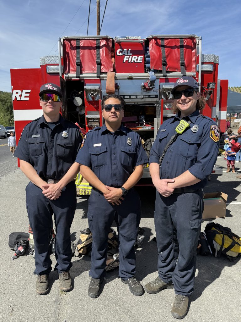 Three CalFire members standing in front of their truck.