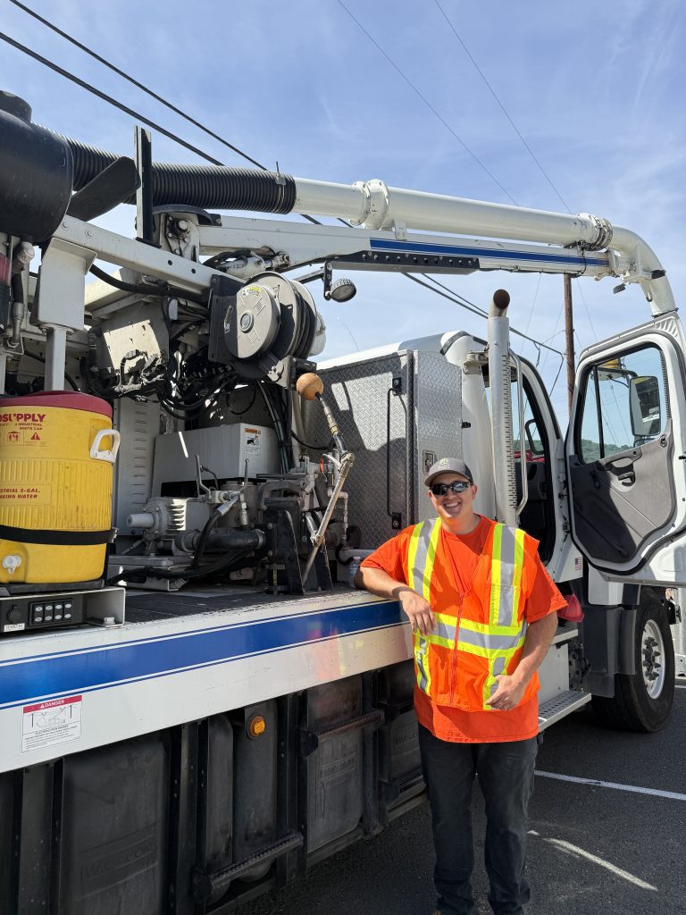 A worker in a neon vest, standing in front of his truck.