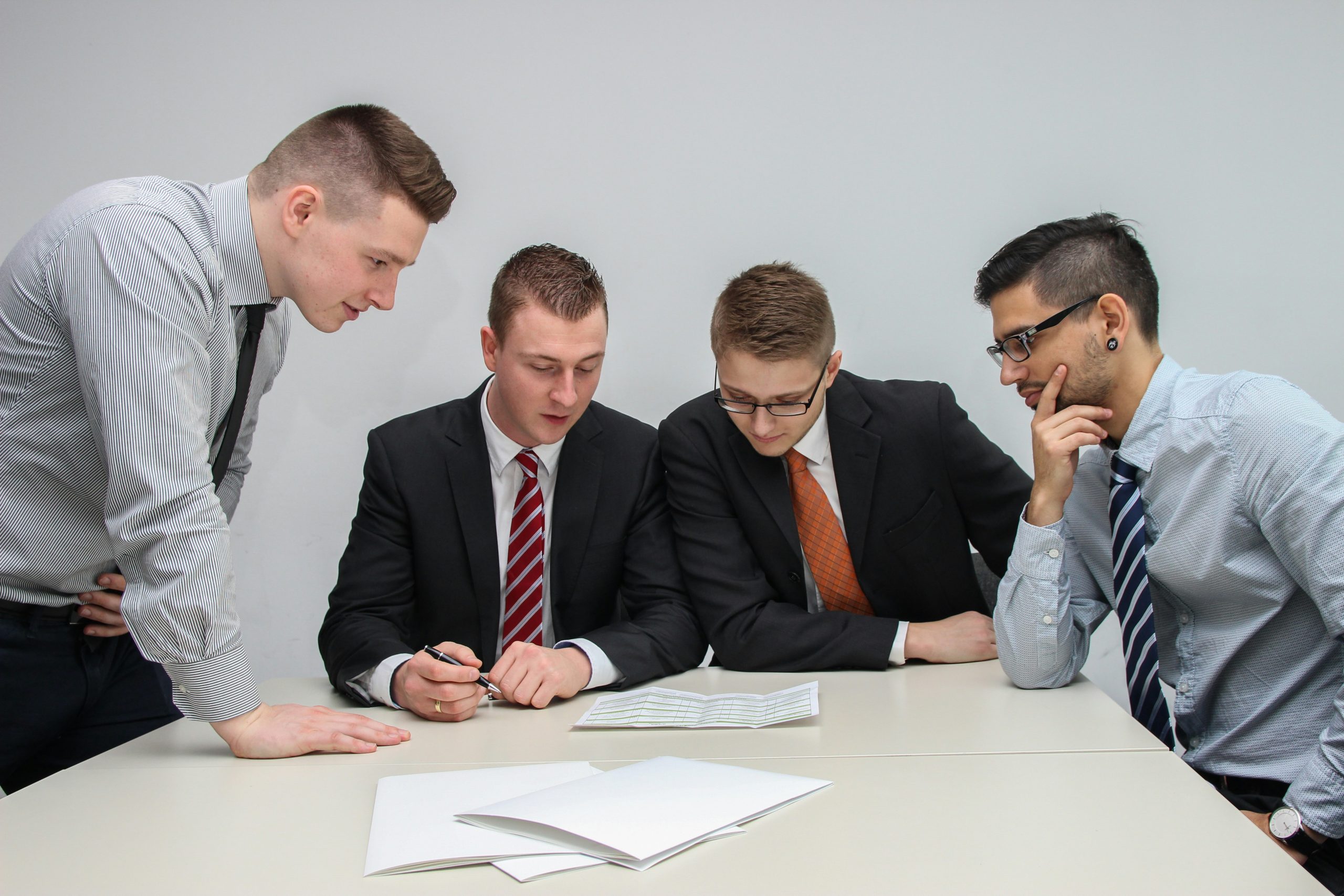 4 business men sitting around a table, looking over AI adoption techniques.